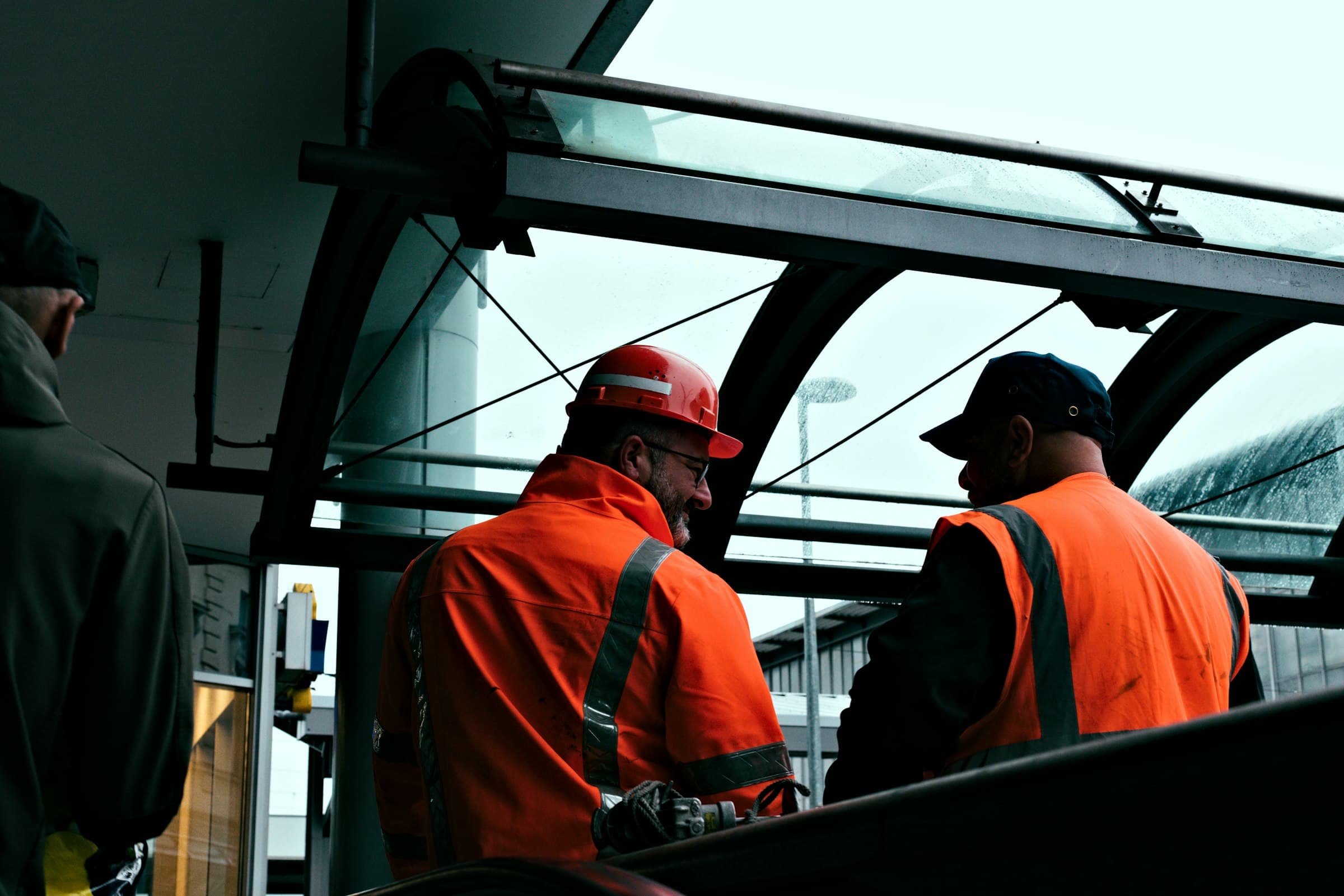 Two workers in orange safety clothing and helmets at work